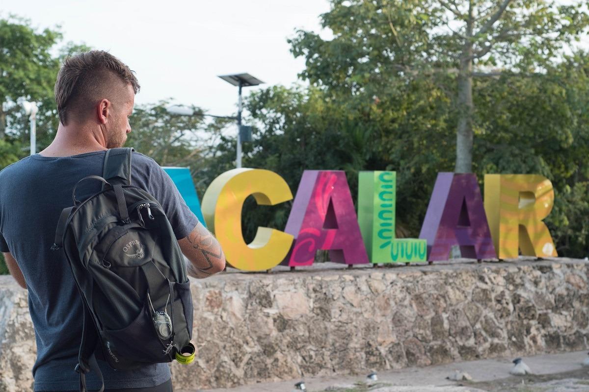 Bojan waiting for the bus before colourful sign for Bacalar (still optimistic that going from Chetumal to Flores in one day will be easy-peasy)