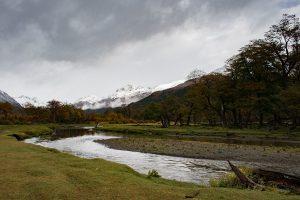 Hiking in Ushuiai cover photo - the river, muddy meadow and snowy mountains in the distance